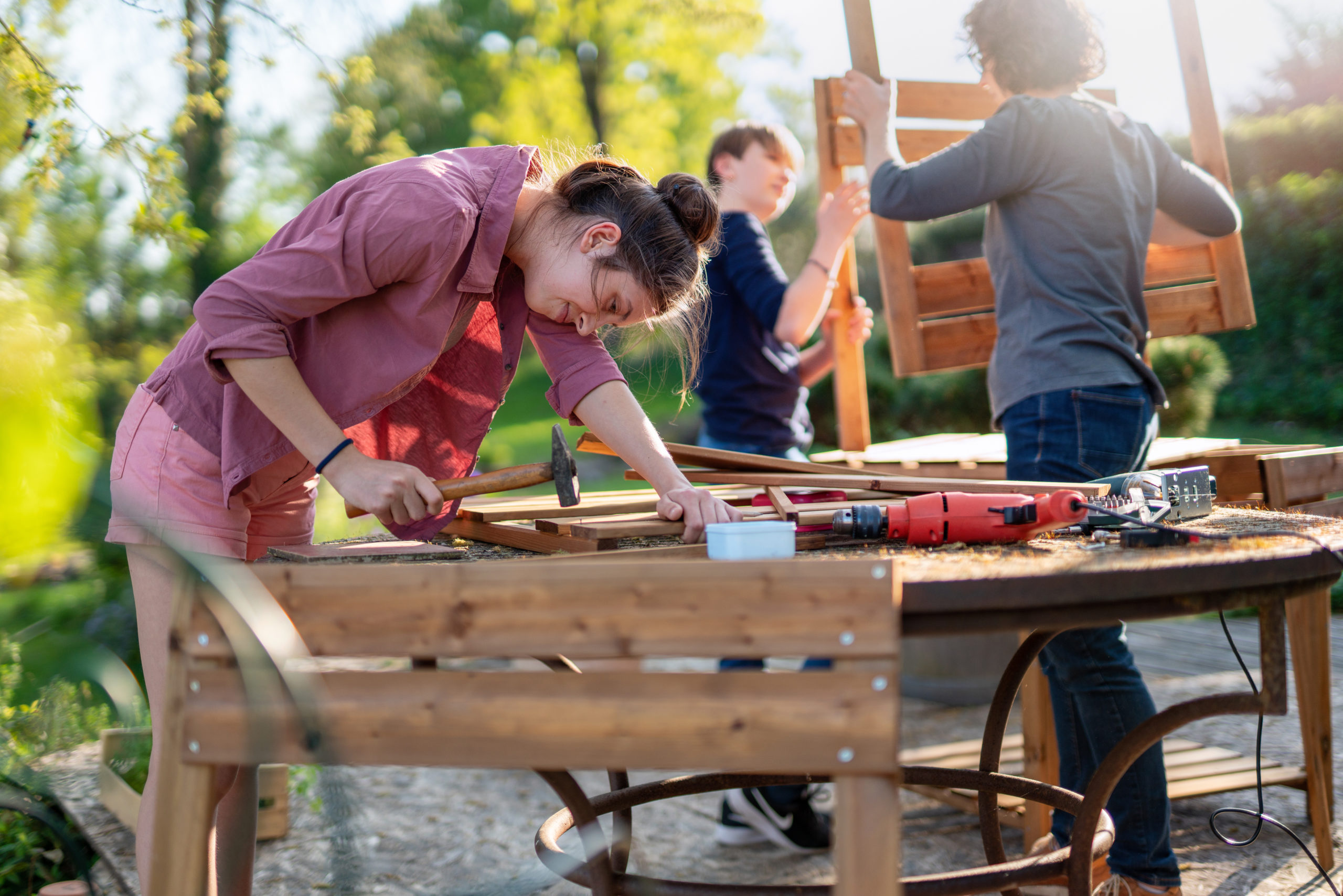 A,Teenage,Girl,Helps,Her,Family,To,Build,Wooden,Planters Photos de jeunes lors d'un chantier participatif de menuiserie.